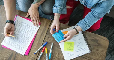 Two people highlighting papers