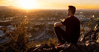 Man watching the sunset from atop a mountain